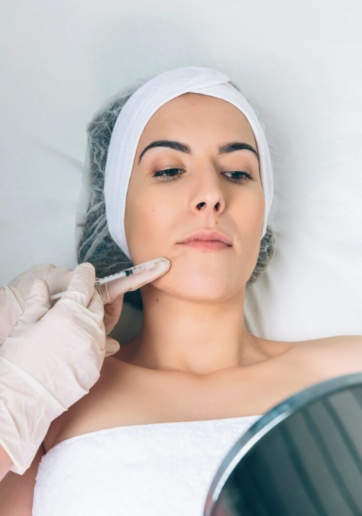 Woman getting facial injections looking at self in mirror